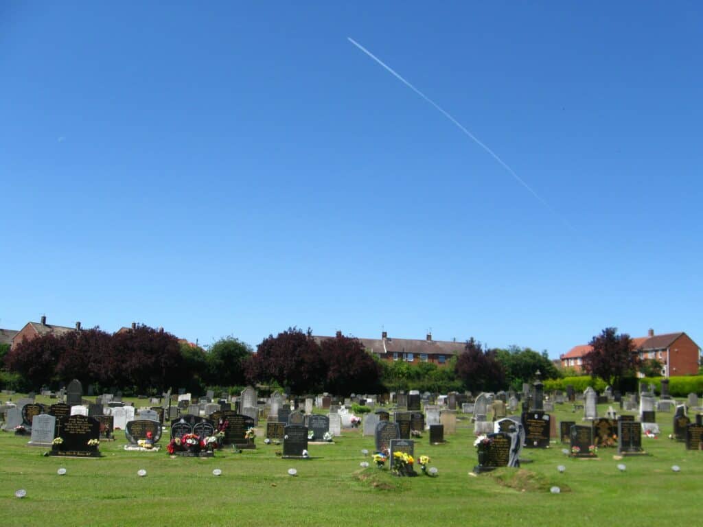 A photo of Butterwick Road Cemetery on a sunny day with a contrail in the sky.